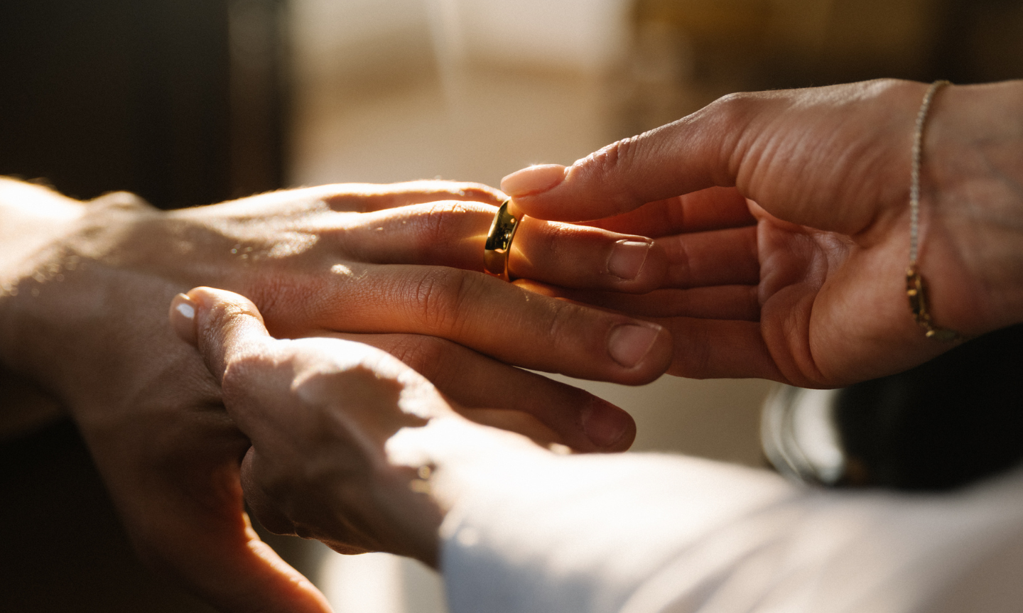 Women putting on her husbands 18ct gold tungsten wedding ring