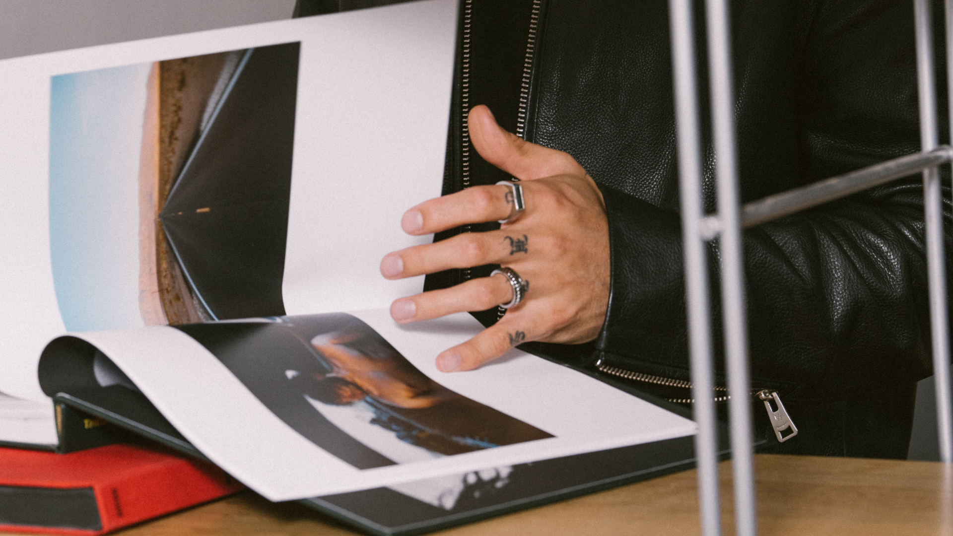 Man flicking through a jewelry style guide catalogue. He's wearing silver rings.