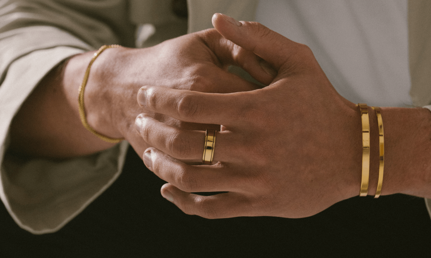 Man wearing minimalist gold jewelry gifts for men including simple bangles and rings